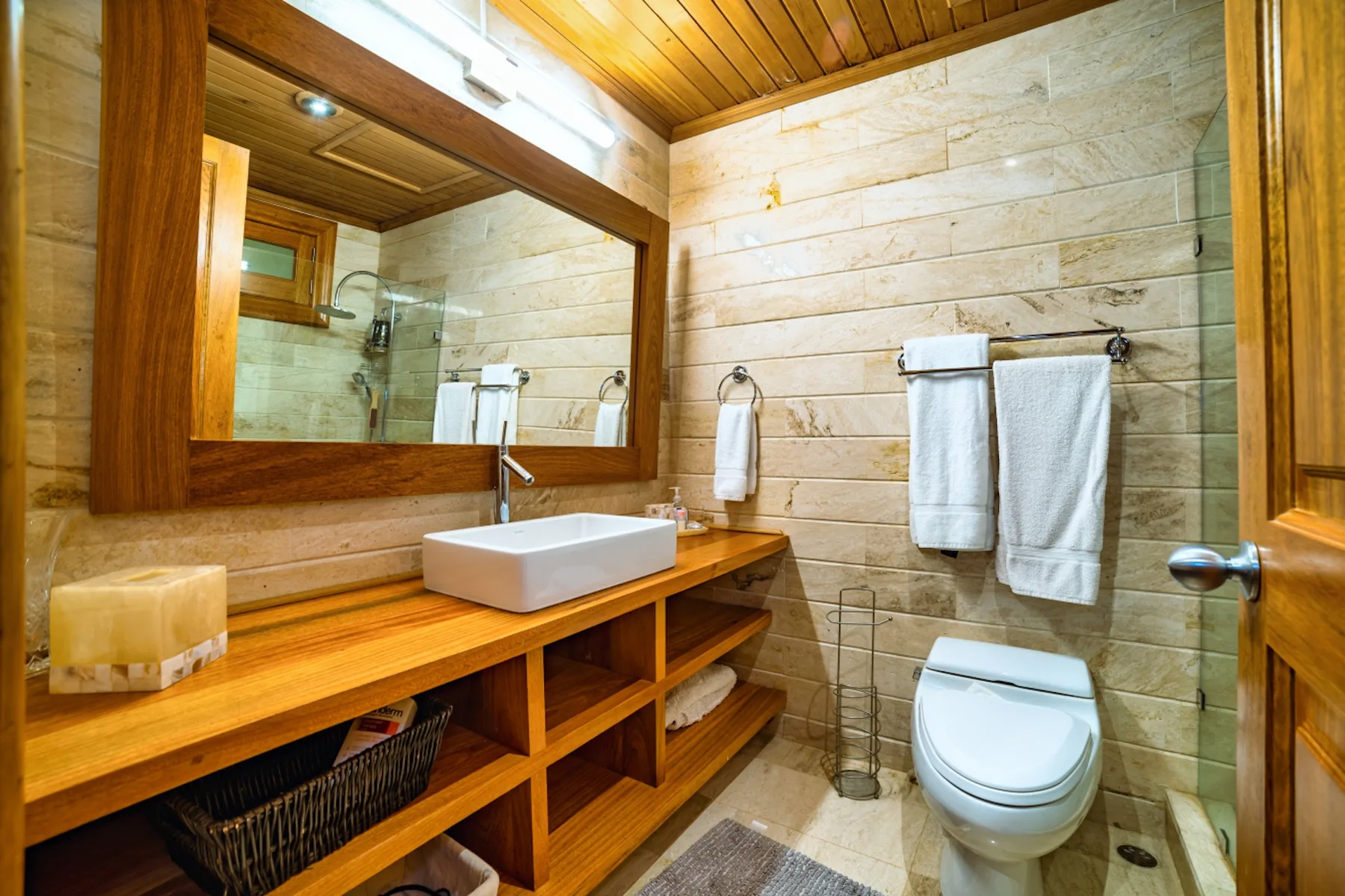 Un baño revestido de madera con lavabo, espejo e inodoro.