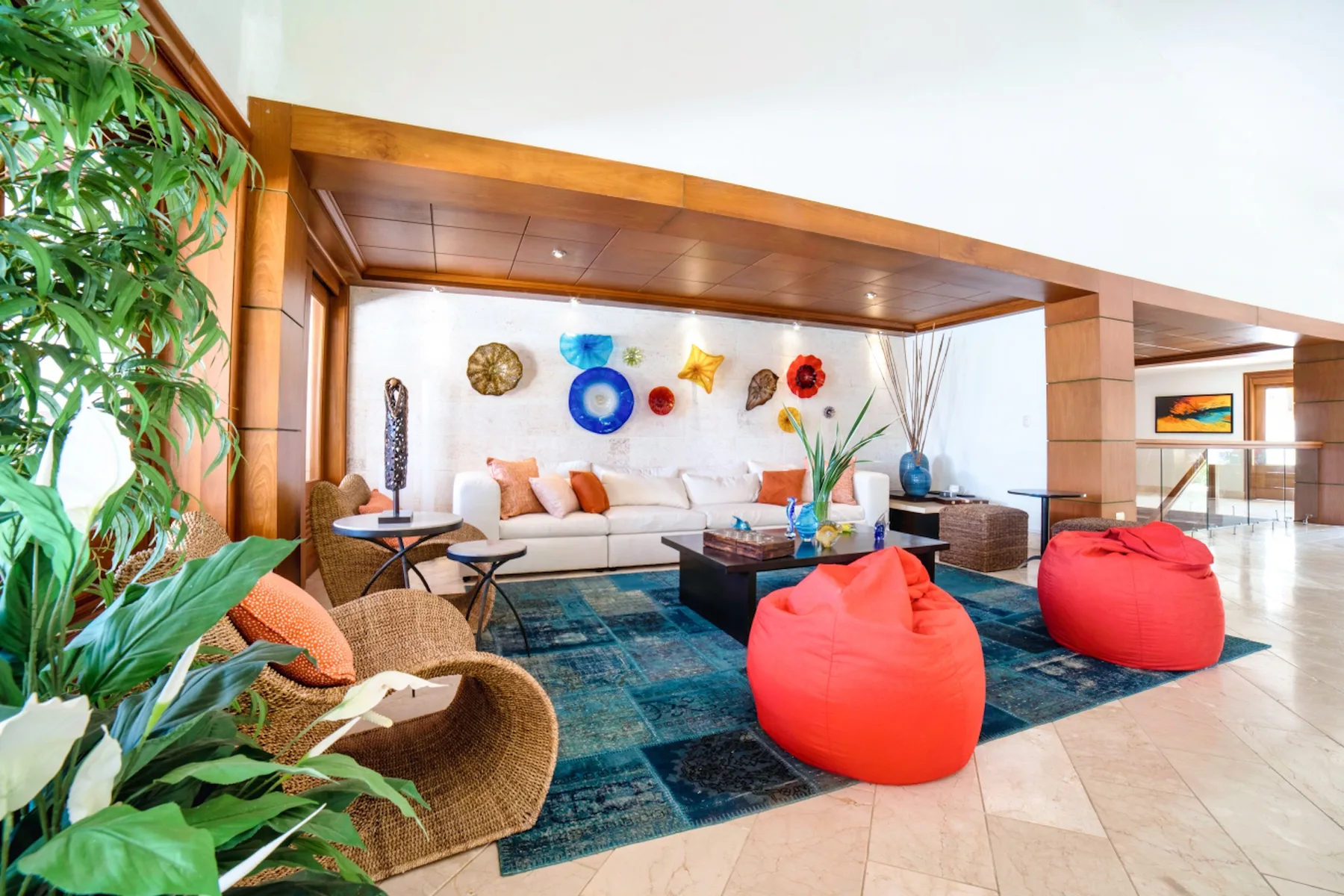 Una zona de estar con asientos, pufs coloridos y arte decorativo en la pared.