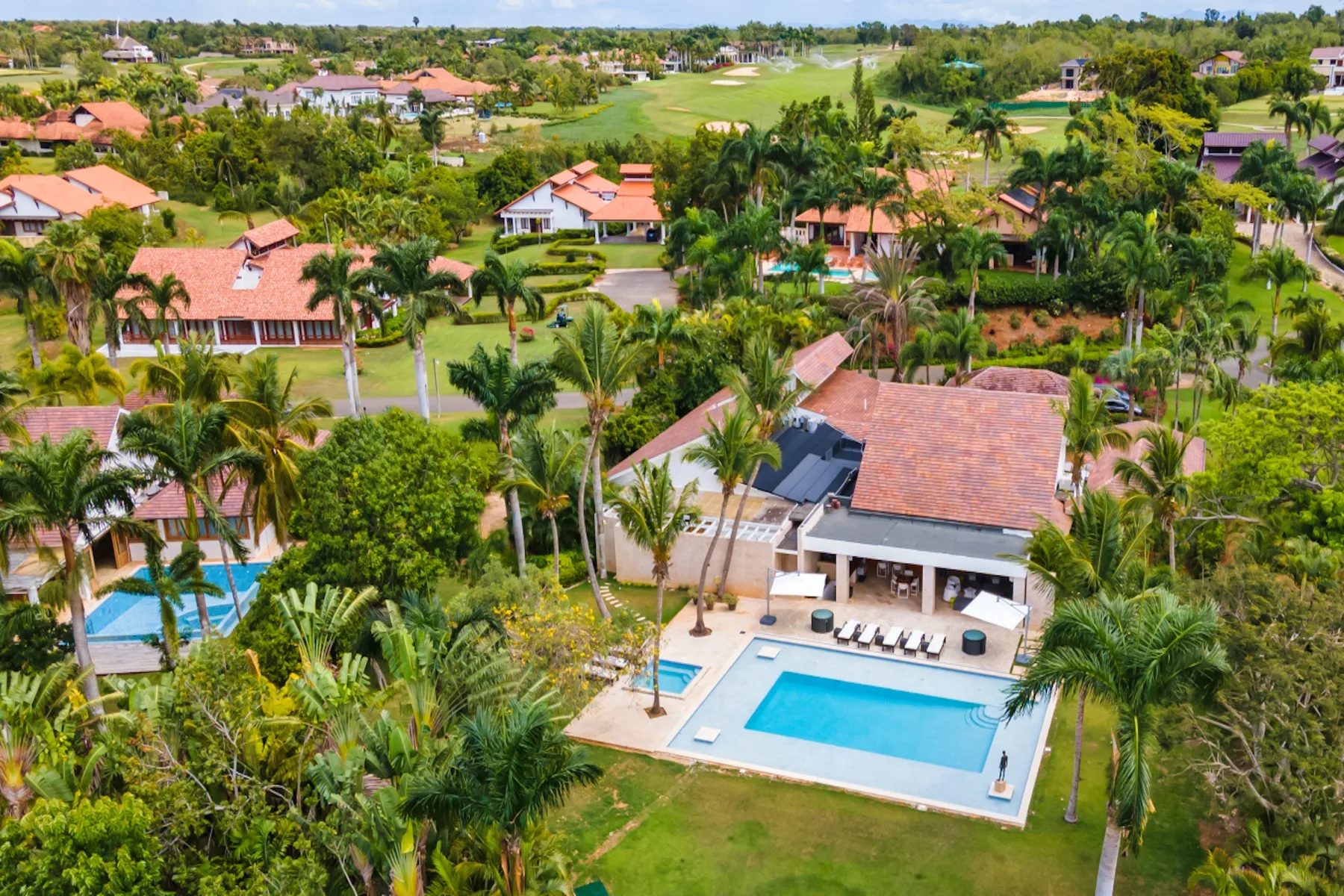 Vista aérea de una piscina junto a una casa, rodeada de abundante vegetación.