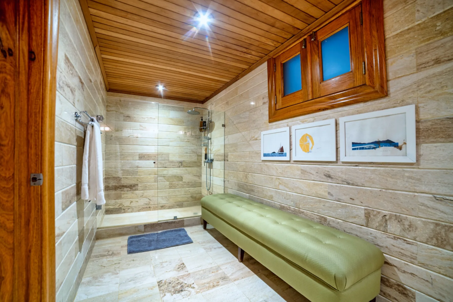 Un baño revestido de baldosas con ducha, banco y cuadros en la pared.