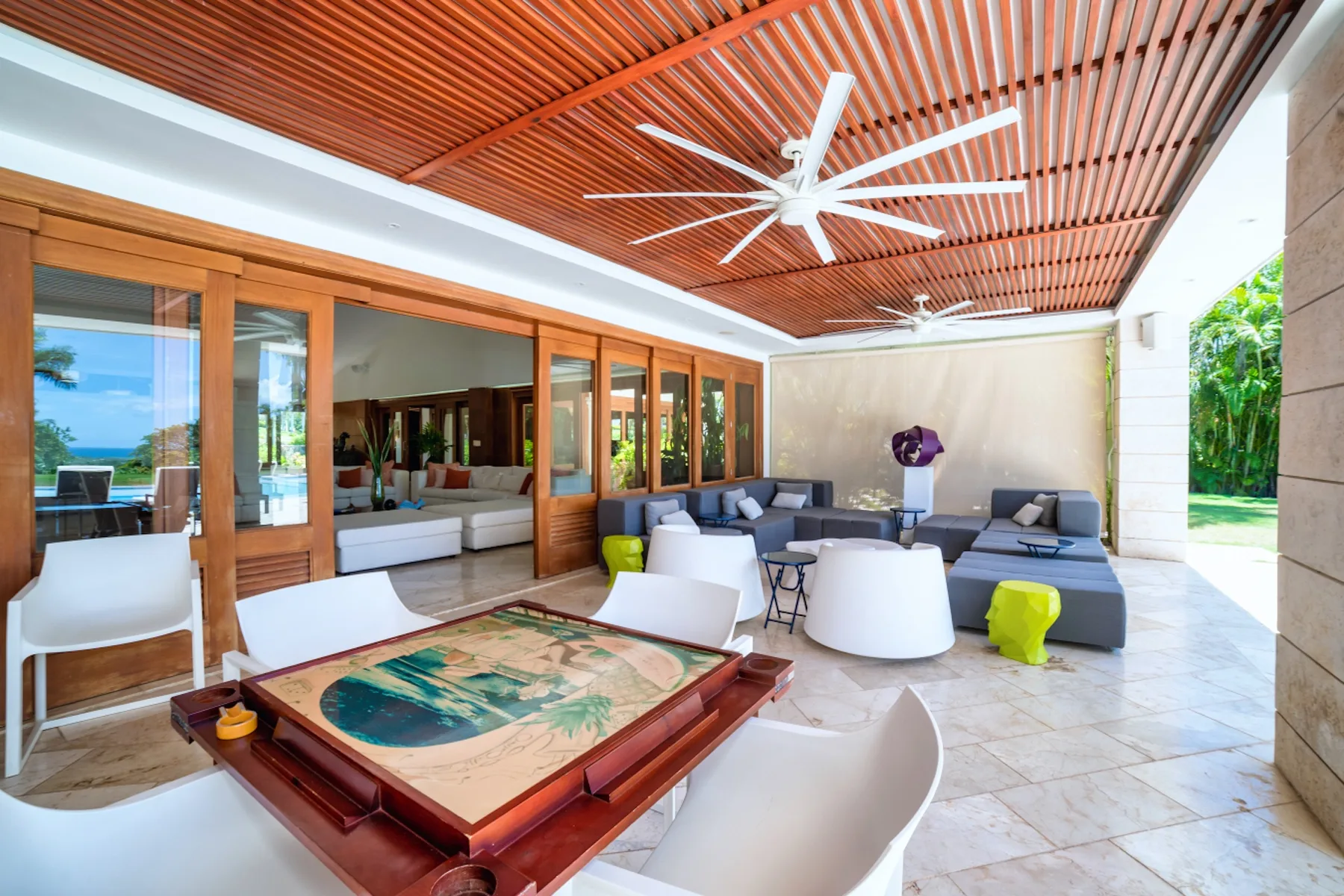 Una sala al aire libre con asientos bajo un techo de listones y ventiladores de techo.