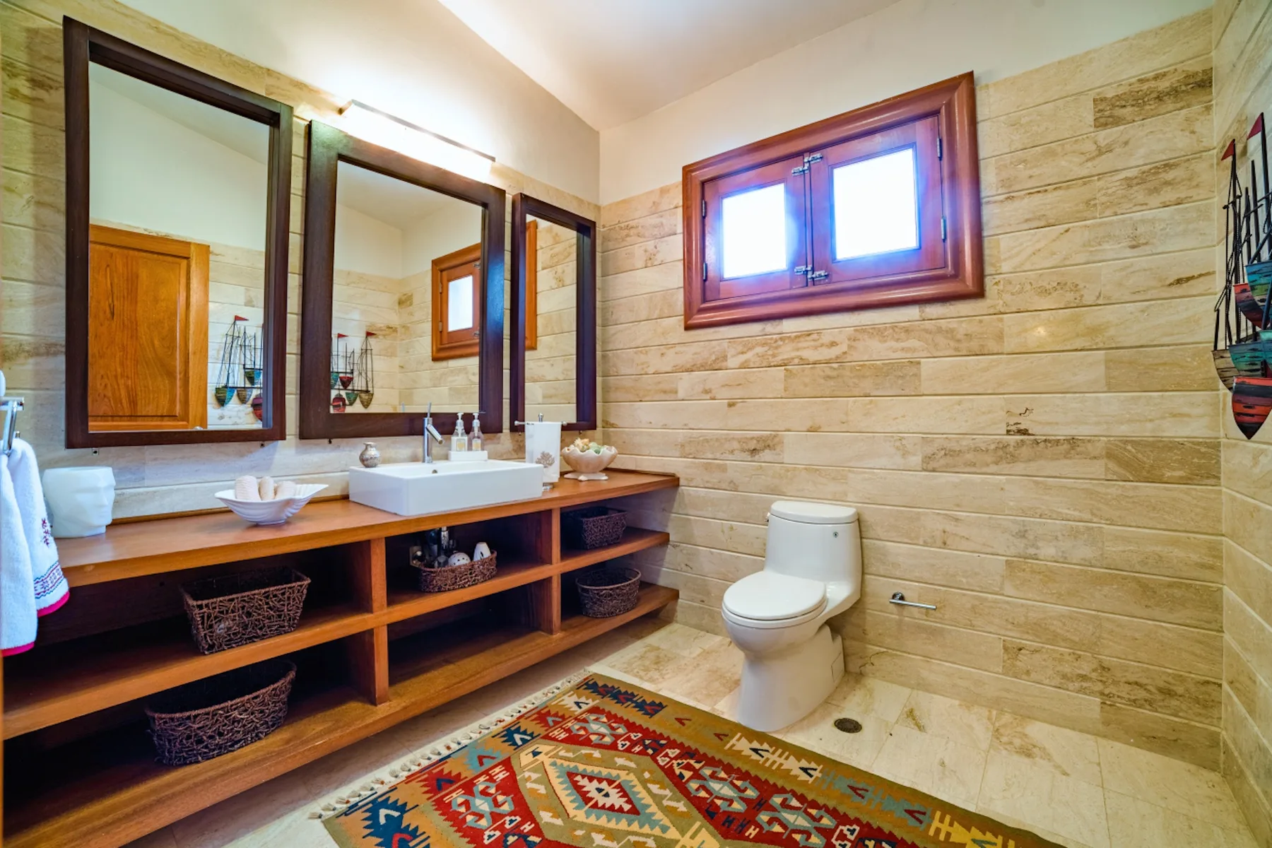 Un baño con un lavabo largo, espejos y un inodoro.