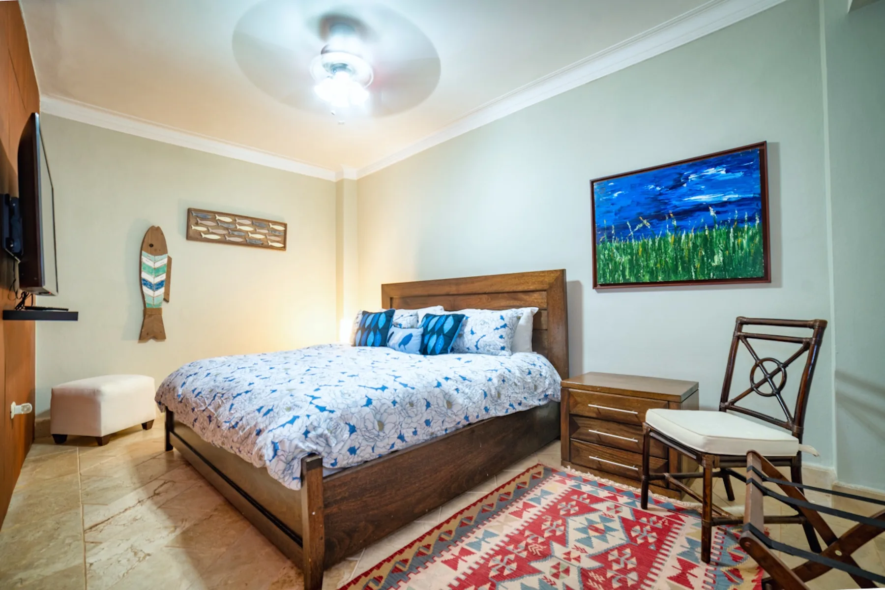 Un dormitorio con una cama de madera, ropa de cama estampada y cuadros enmarcados.
