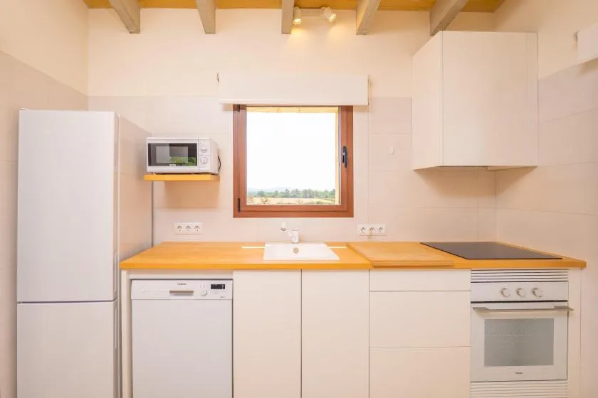 A bright kitchen with wooden countertops, white cabinets, and a window above the sink.