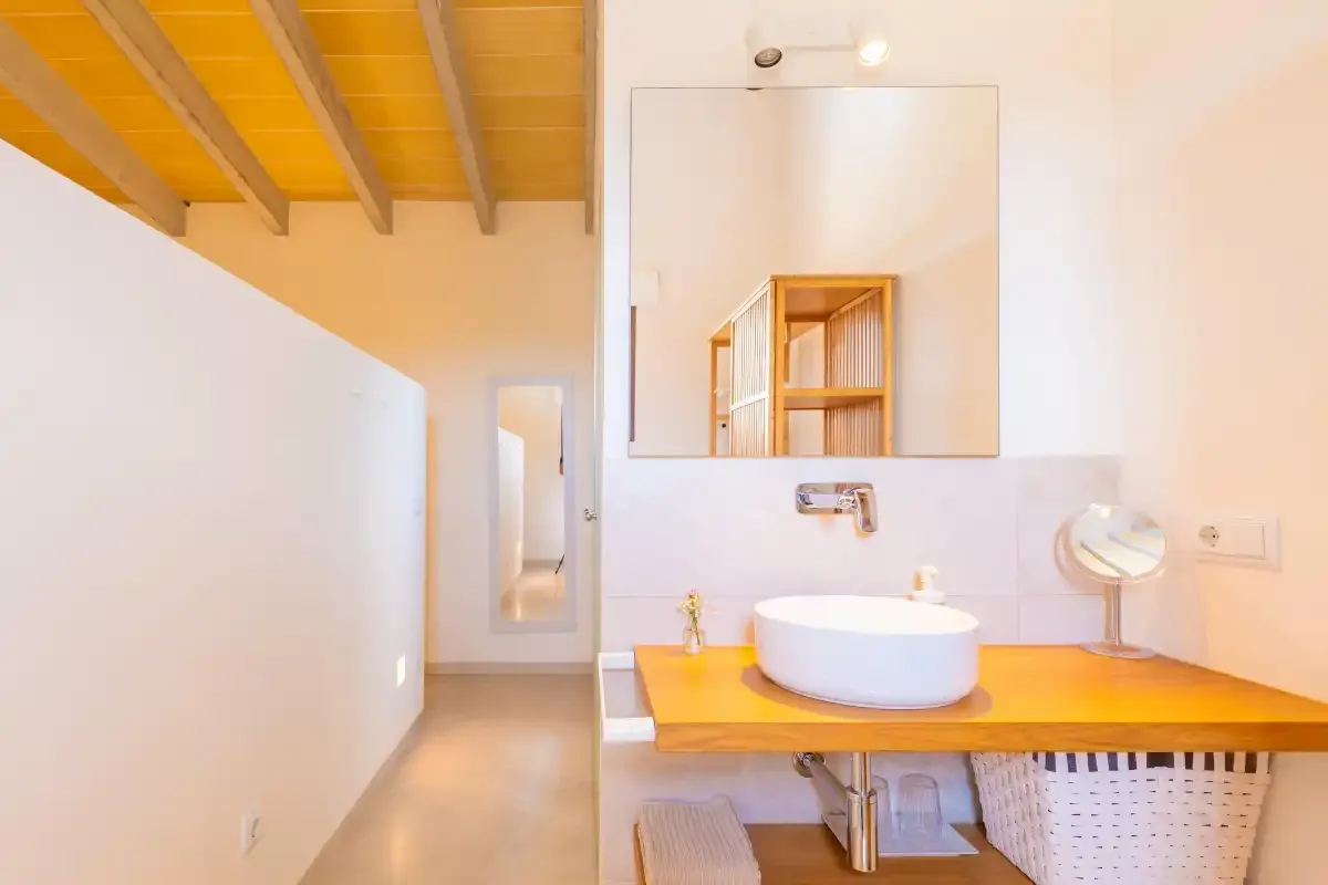 A bathroom with a white vessel sink on a wooden counter and a large mirror.