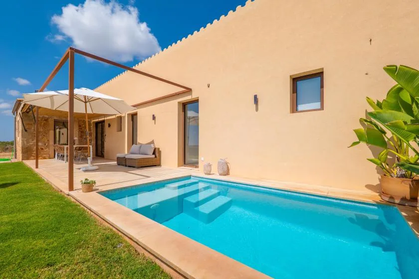 A swimming pool beside a patio with outdoor seating and a shade canopy.