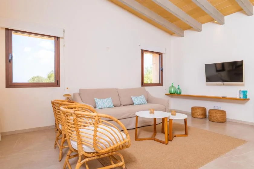 A bright living room with seating, a coffee table, and a wall-mounted television.