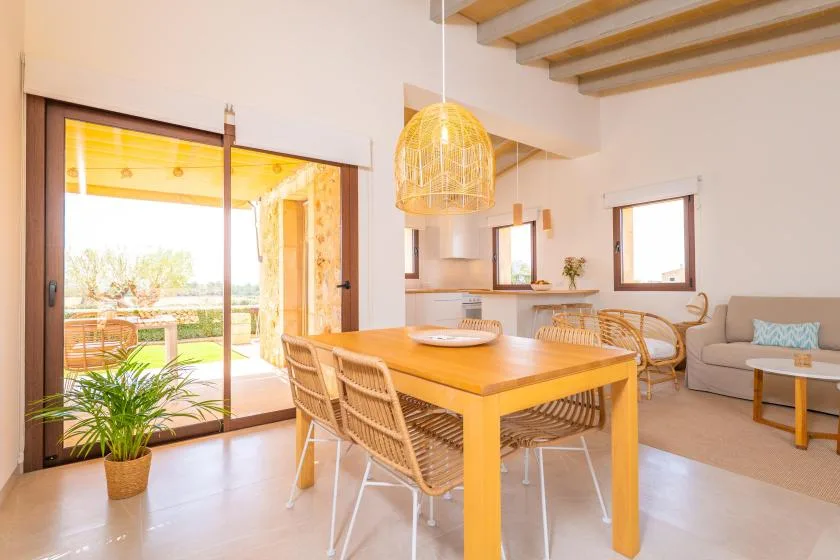 A bright dining and living area with a wooden table and sliding glass doors.