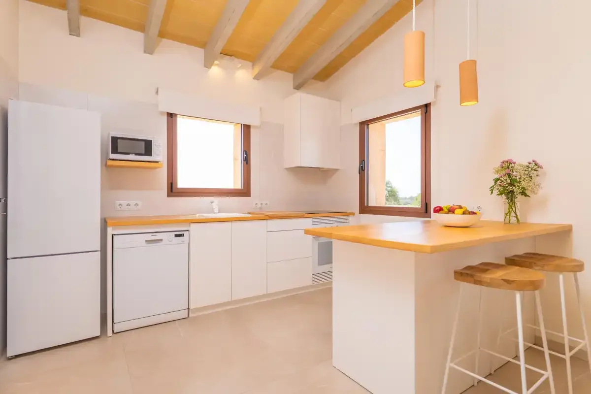 A bright kitchen with white cabinets, a refrigerator, and a central island.