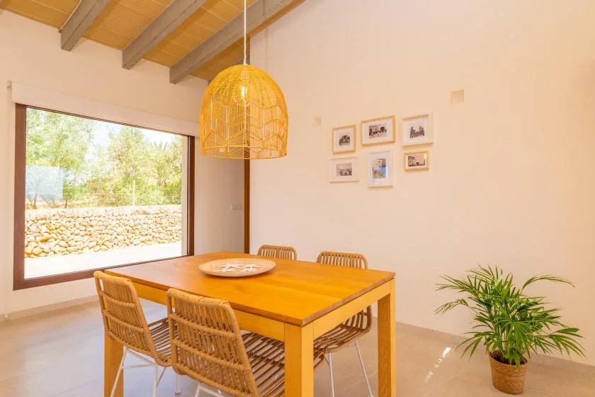 A dining area with a wooden table, woven seating, and a large window.