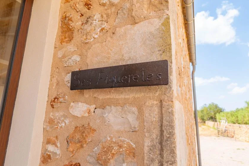 A stone exterior wall with a dark name plaque beside a doorway.