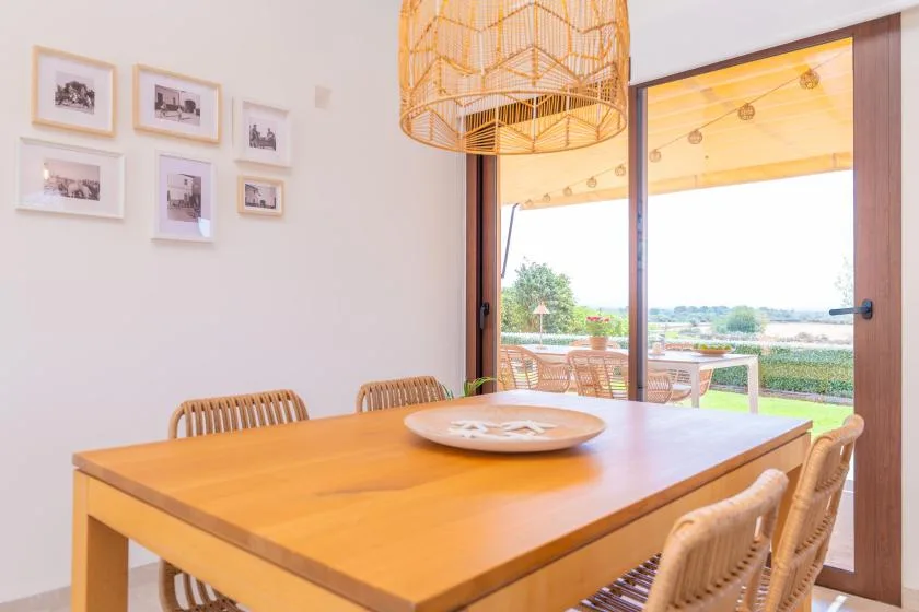 A dining area with a wooden table beside open sliding glass doors.