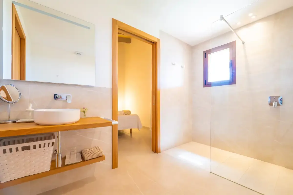A bathroom with a wooden vanity and a glass shower screen.