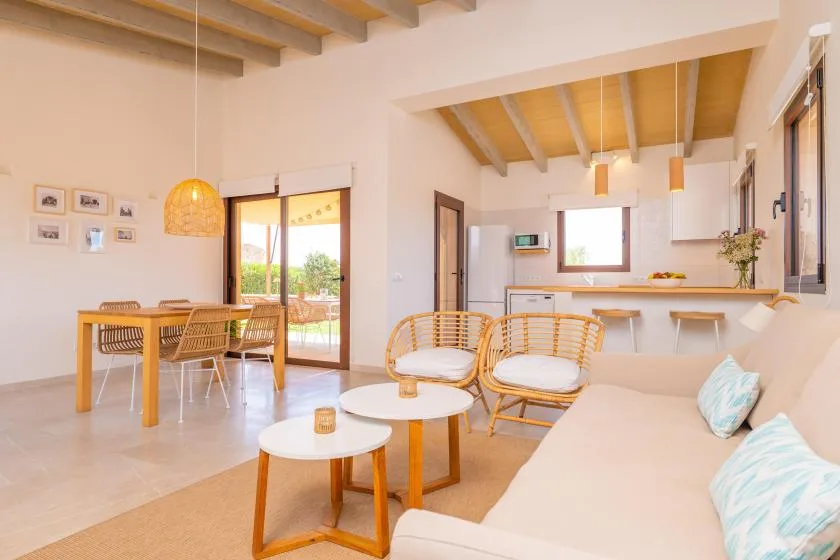 A bright open-plan living and dining area with a kitchen counter and pale seating.