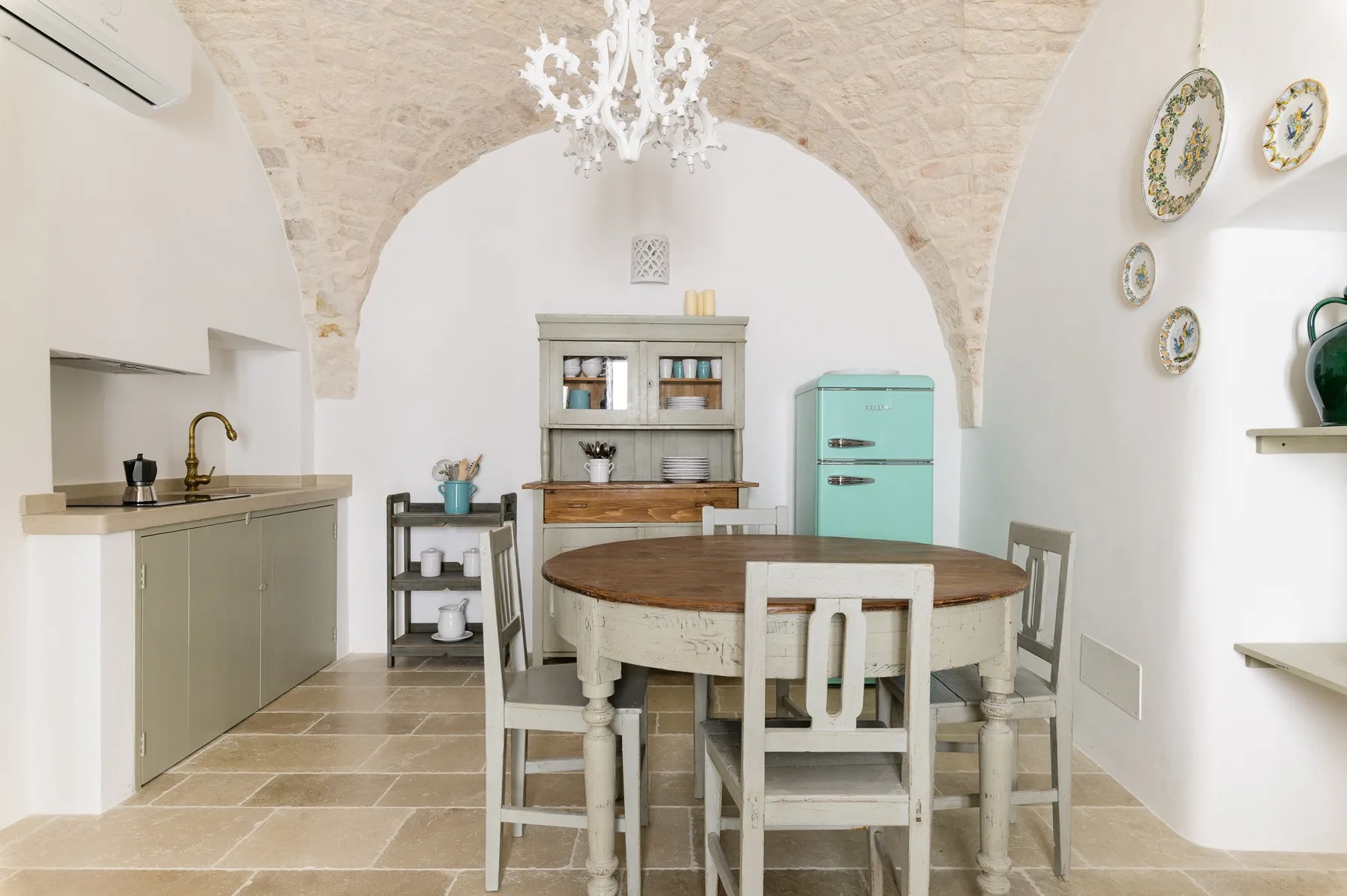 A dining area with a round wooden table beneath a vaulted stone arch.