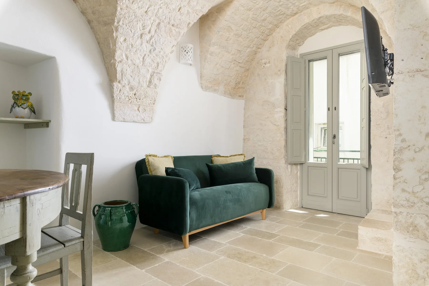 A living room with a green sofa beneath a stone arch.