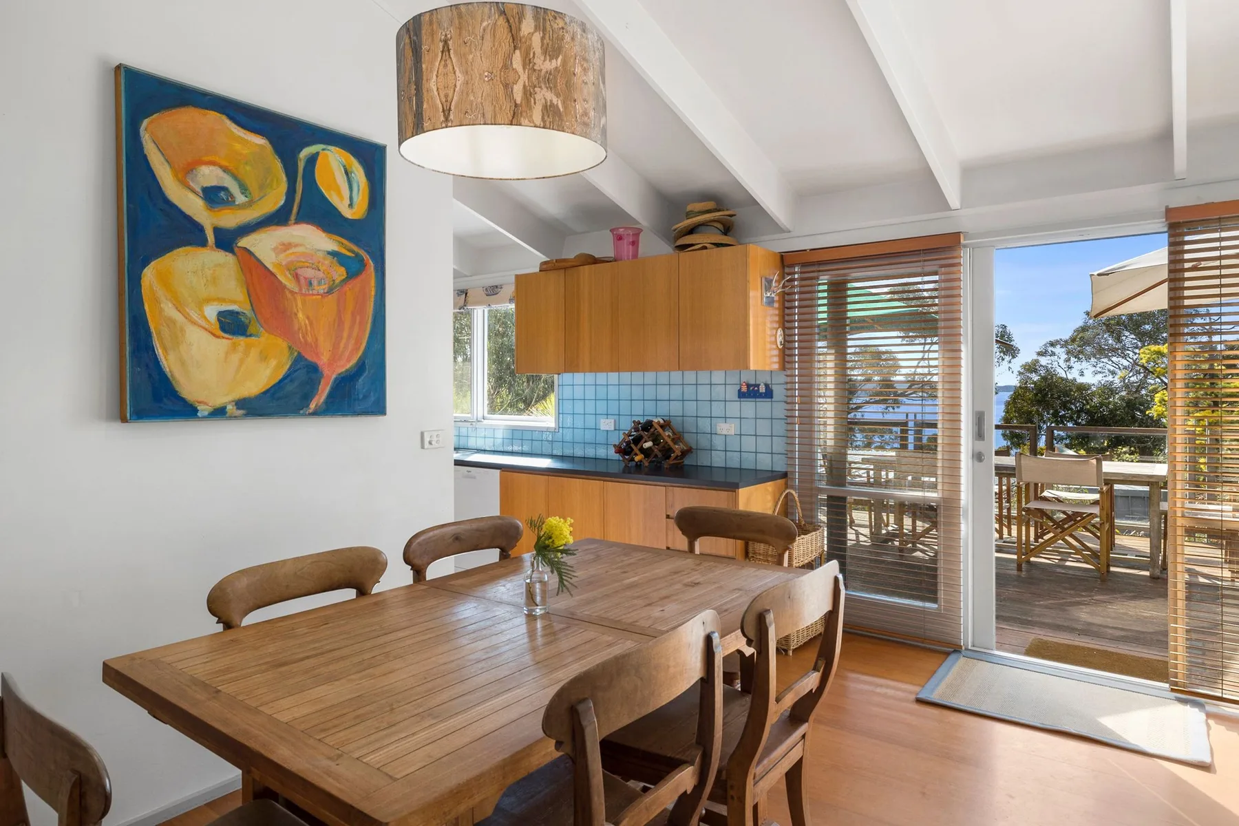 A dining area with a wooden table beside a glass door opening to a patio.