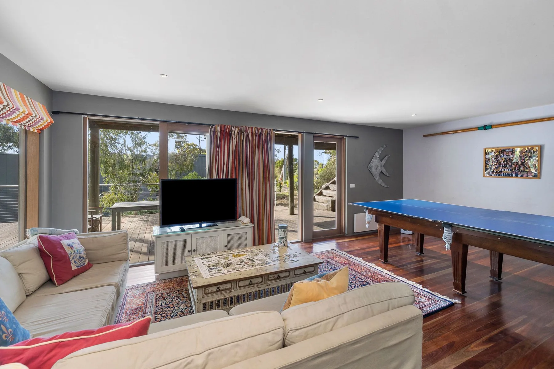 A living room with seating, a television, and a pool table.