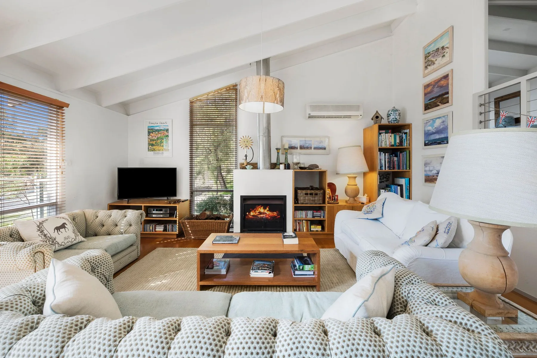 A bright living room with seating, a fireplace, and a television.