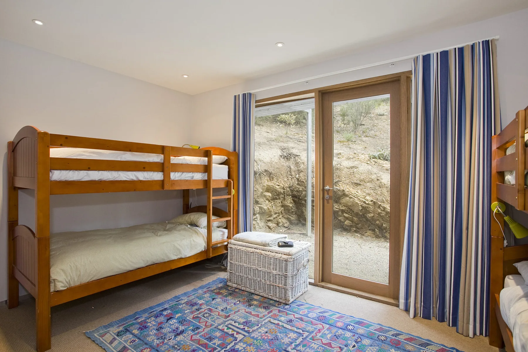 A bedroom with wooden bunk beds beside a glass patio door.