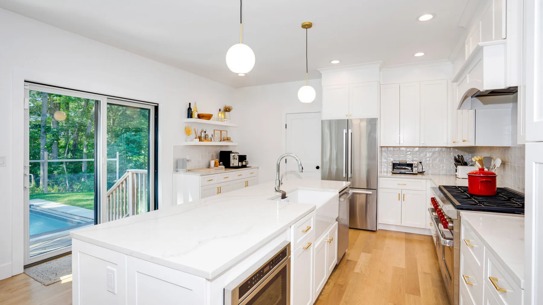 A bright kitchen with a large island and sliding glass doors opening onto a patio.