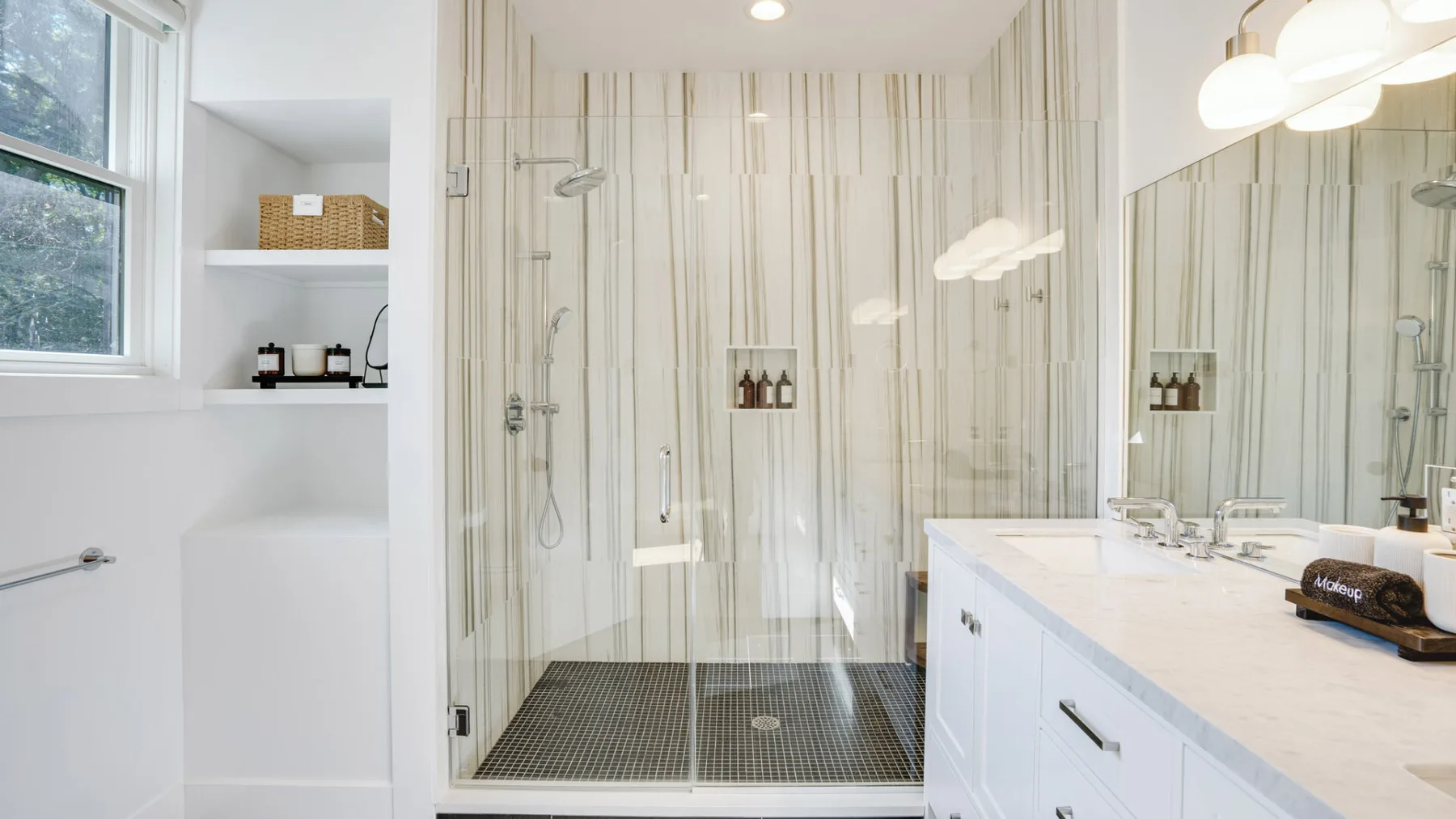 A bright bathroom with a glass-enclosed shower and a long vanity.