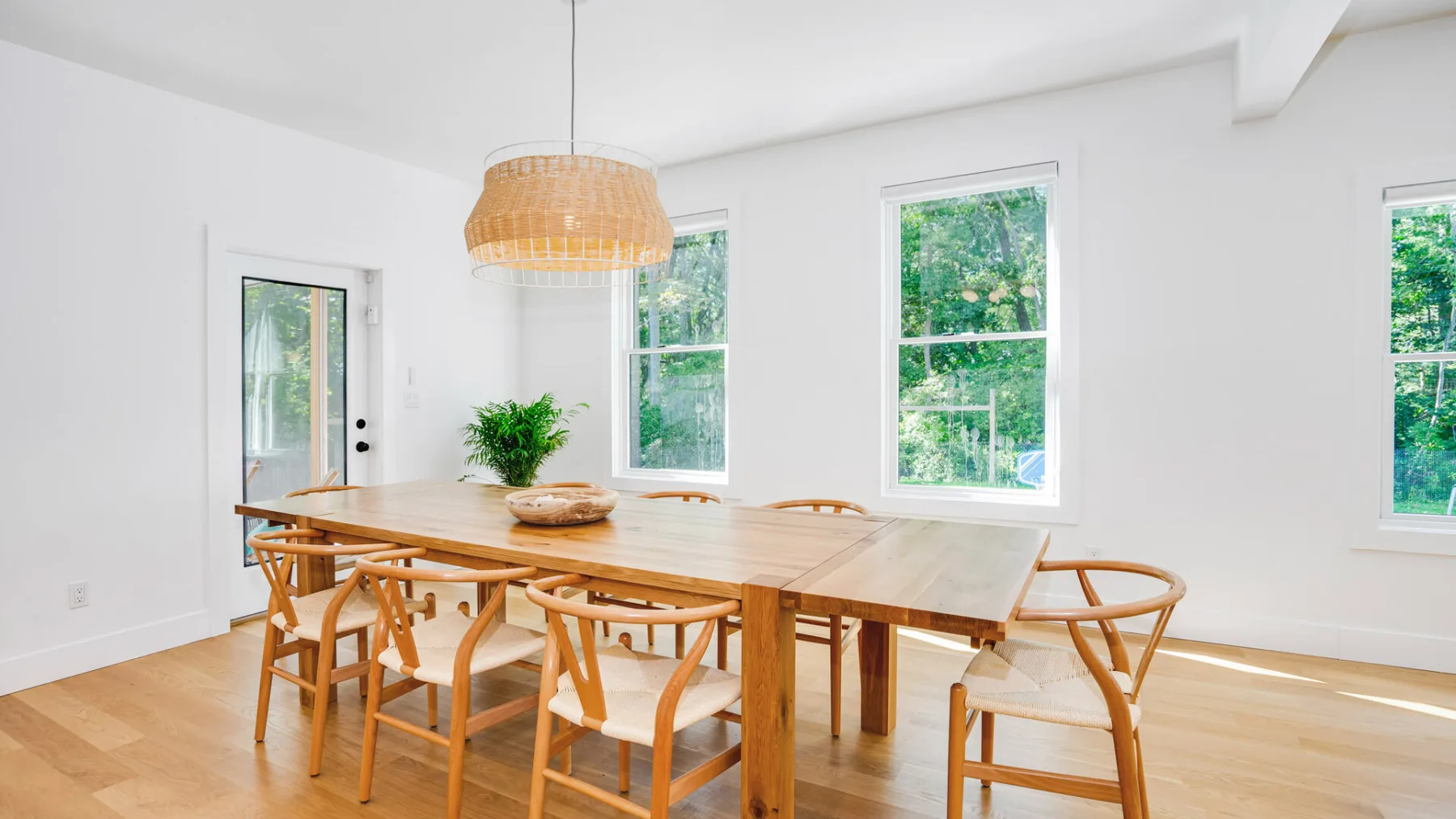 A bright dining room with a long wooden table and large windows.