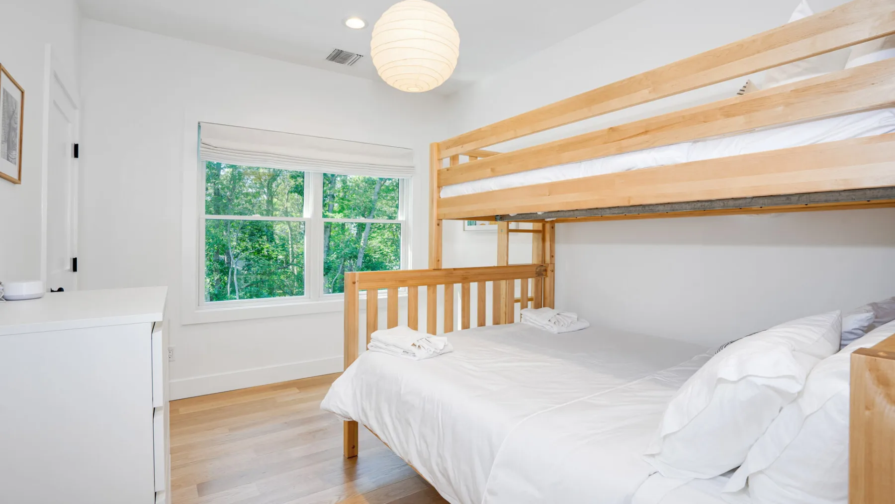 A bright bedroom with a large bed beneath a wooden loft bed.