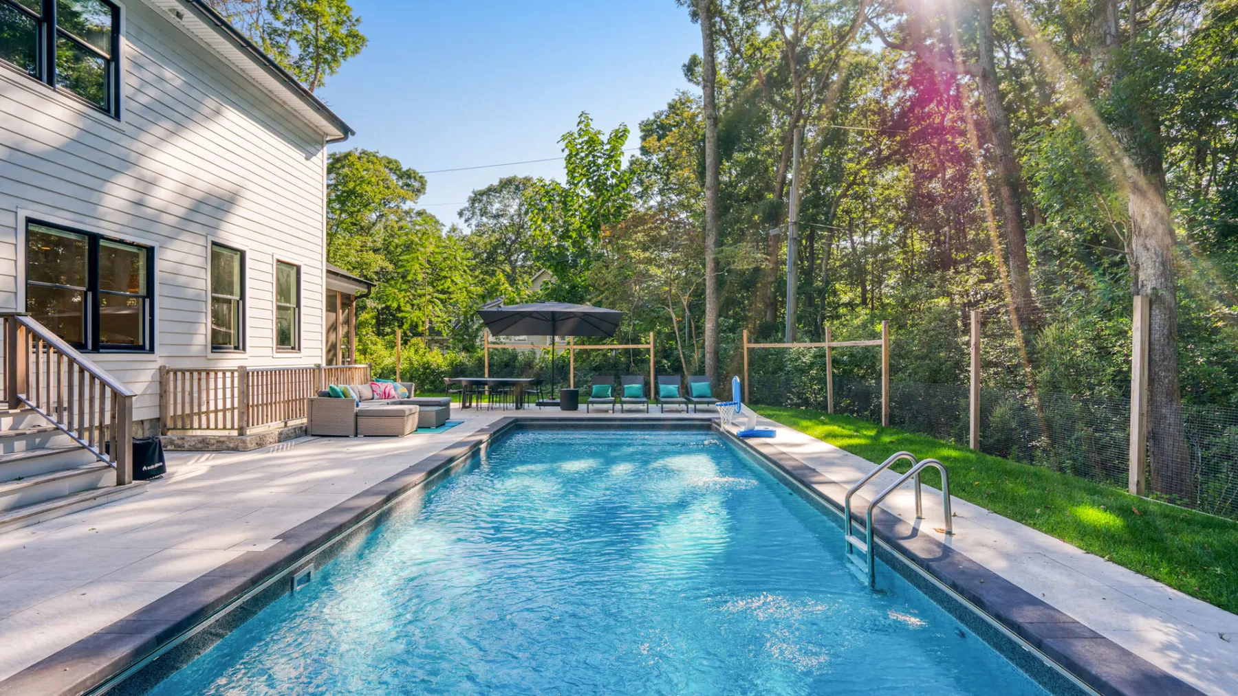 An outdoor swimming pool beside a house, surrounded by trees.