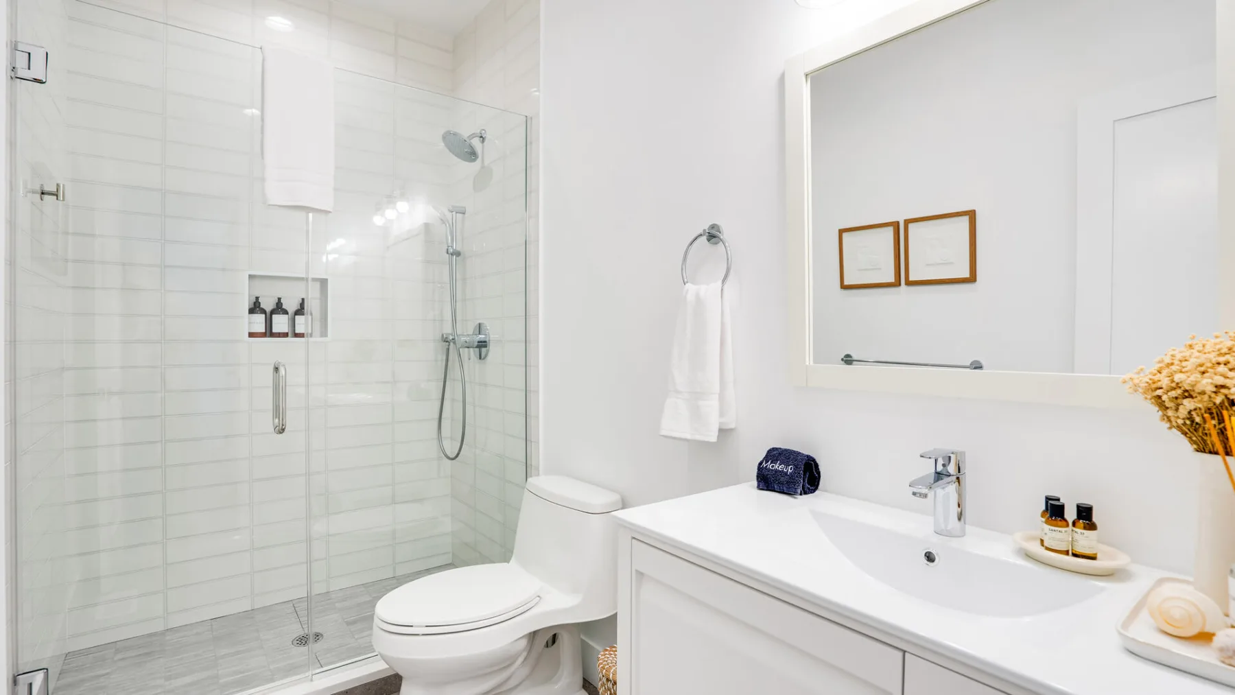 A bright bathroom with a glass shower, toilet, and wide vanity.