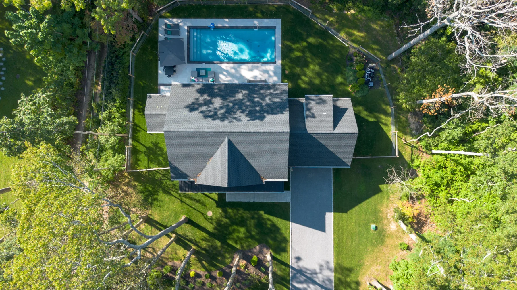 An aerial view shows a house, swimming pool, and surrounding green yard.