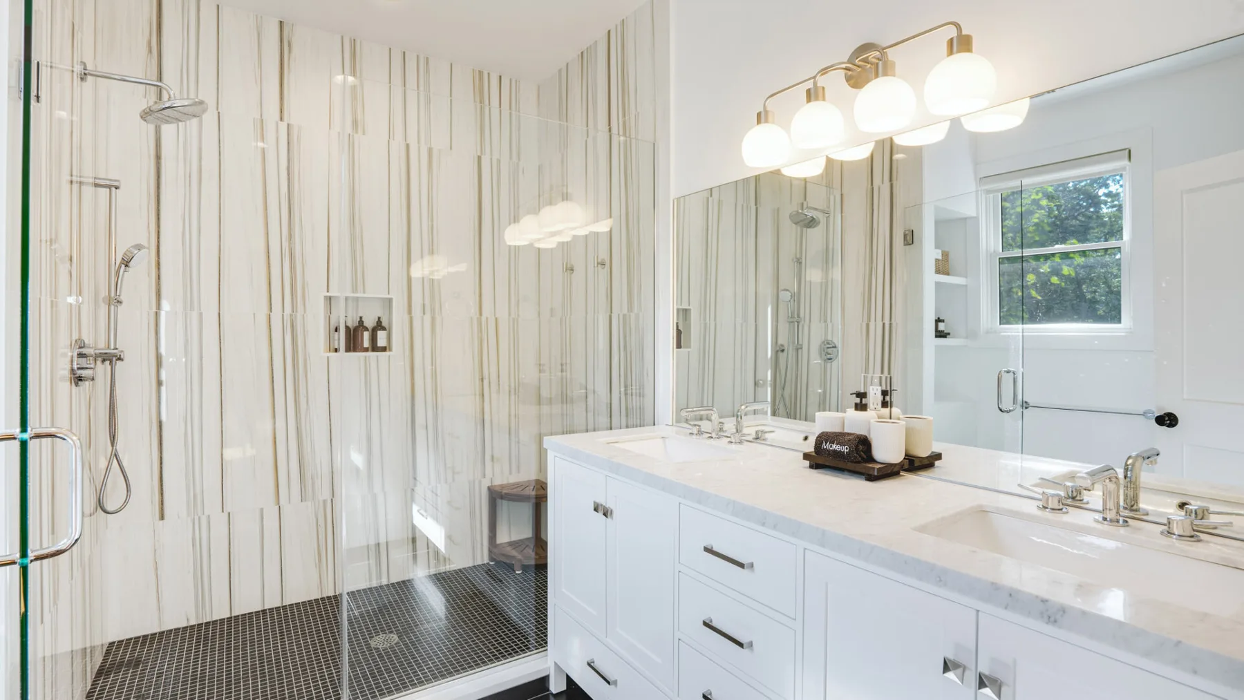 A bright bathroom with a glass-enclosed shower and a long white vanity.