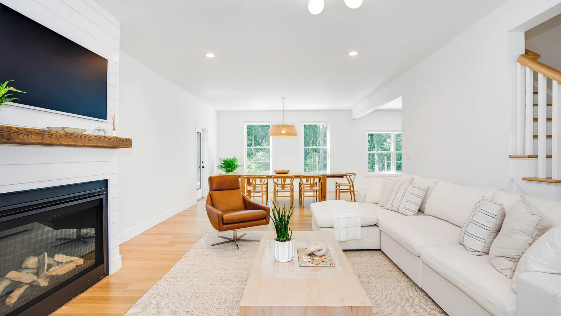 A bright living room with a fireplace, seating, and a dining area in the background.