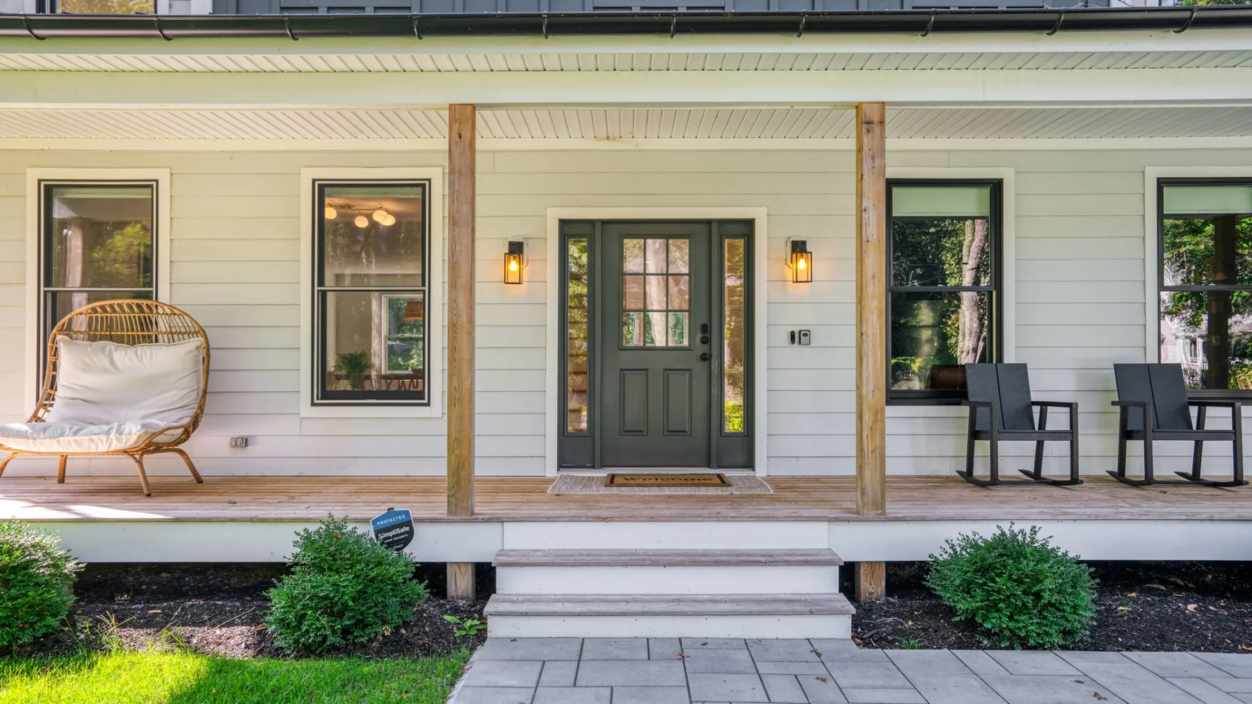 A covered front porch with a central entry door, windows, and steps.