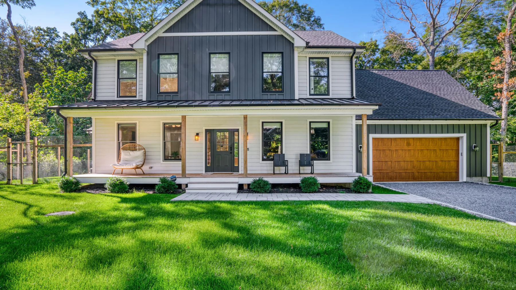 A two-story house with a covered porch, attached garage, and green front lawn.