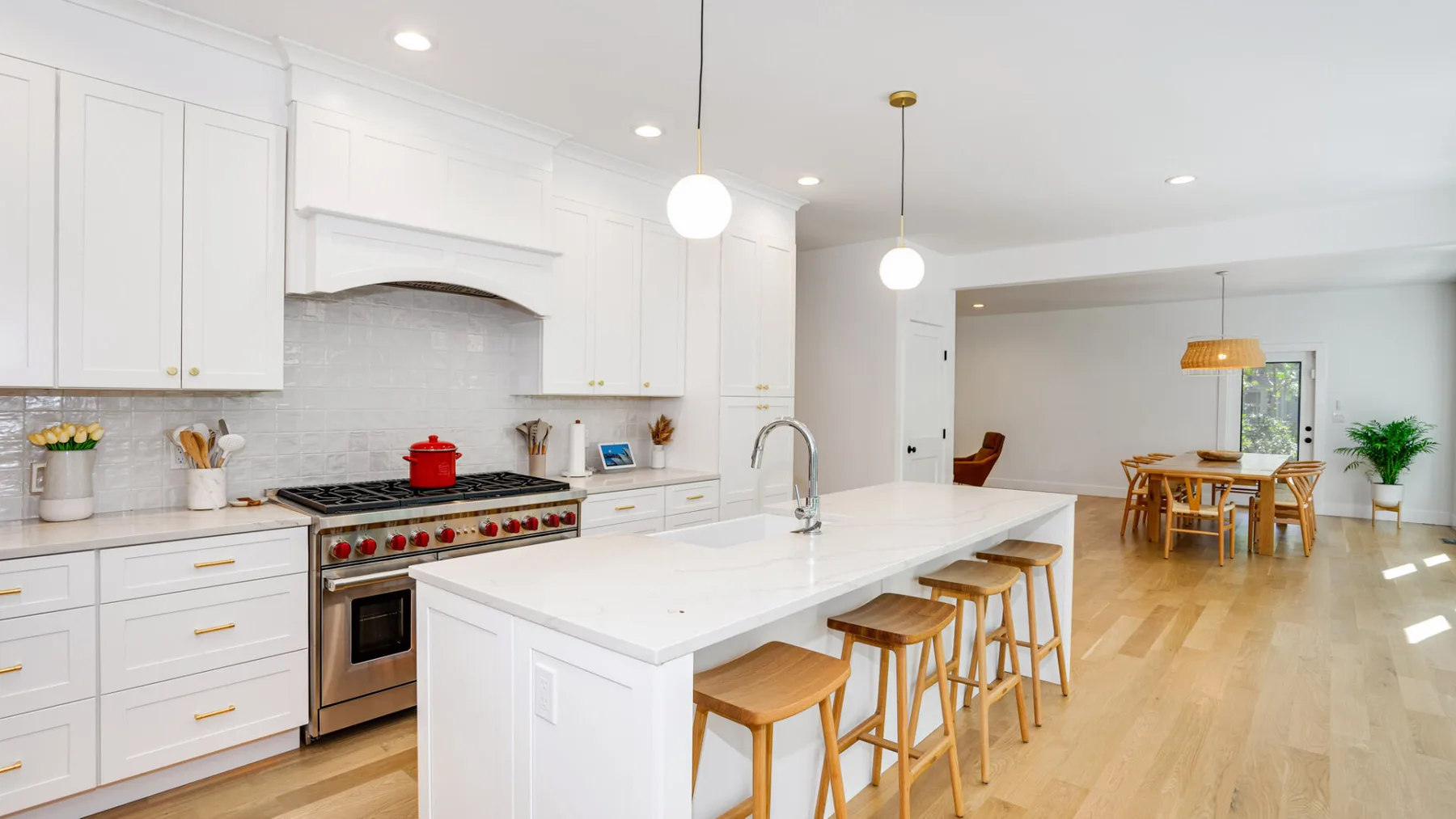 A bright kitchen with a large island and dining area beyond.