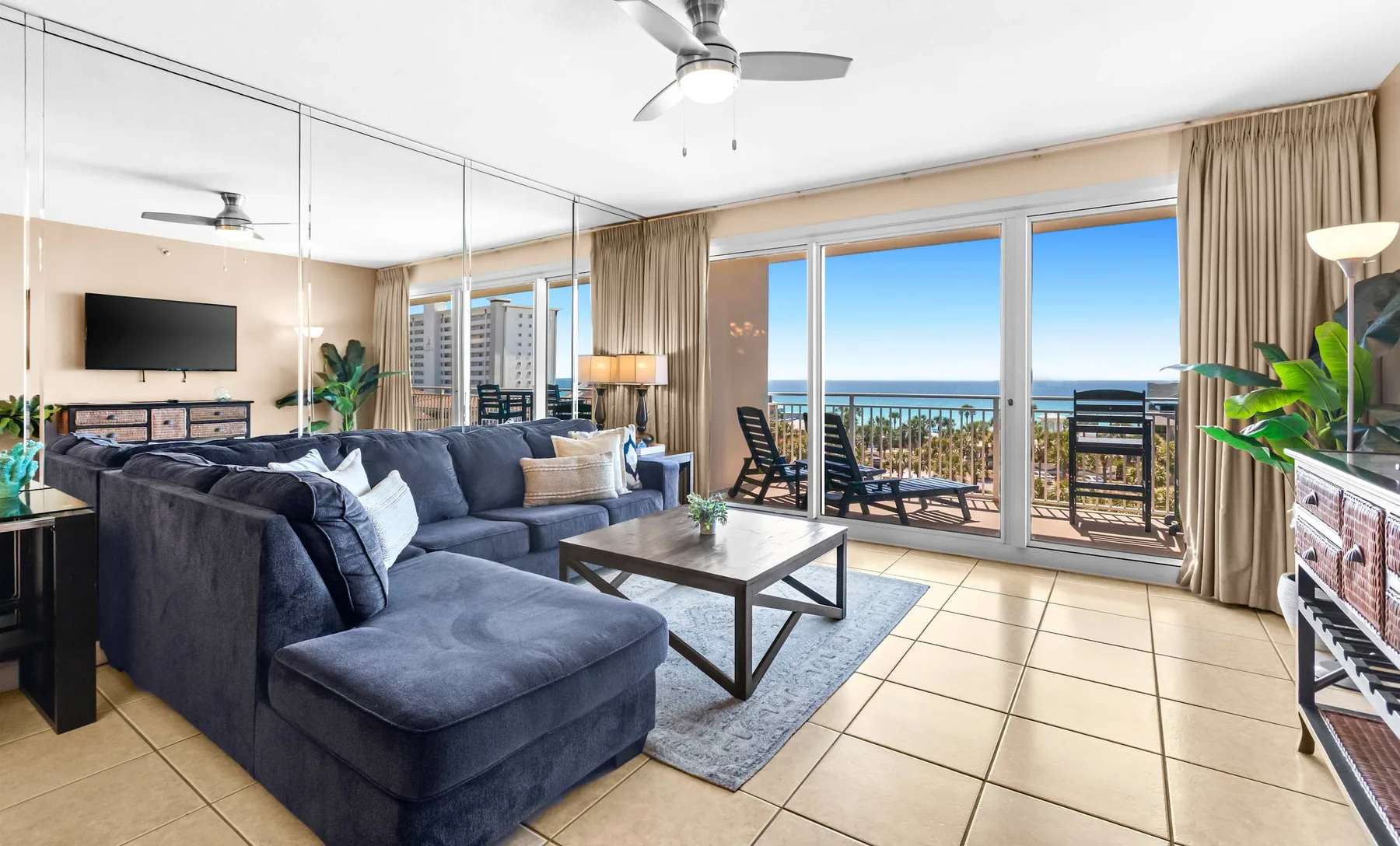 A living room with seating and a coffee table beside glass doors opening to a balcony.
