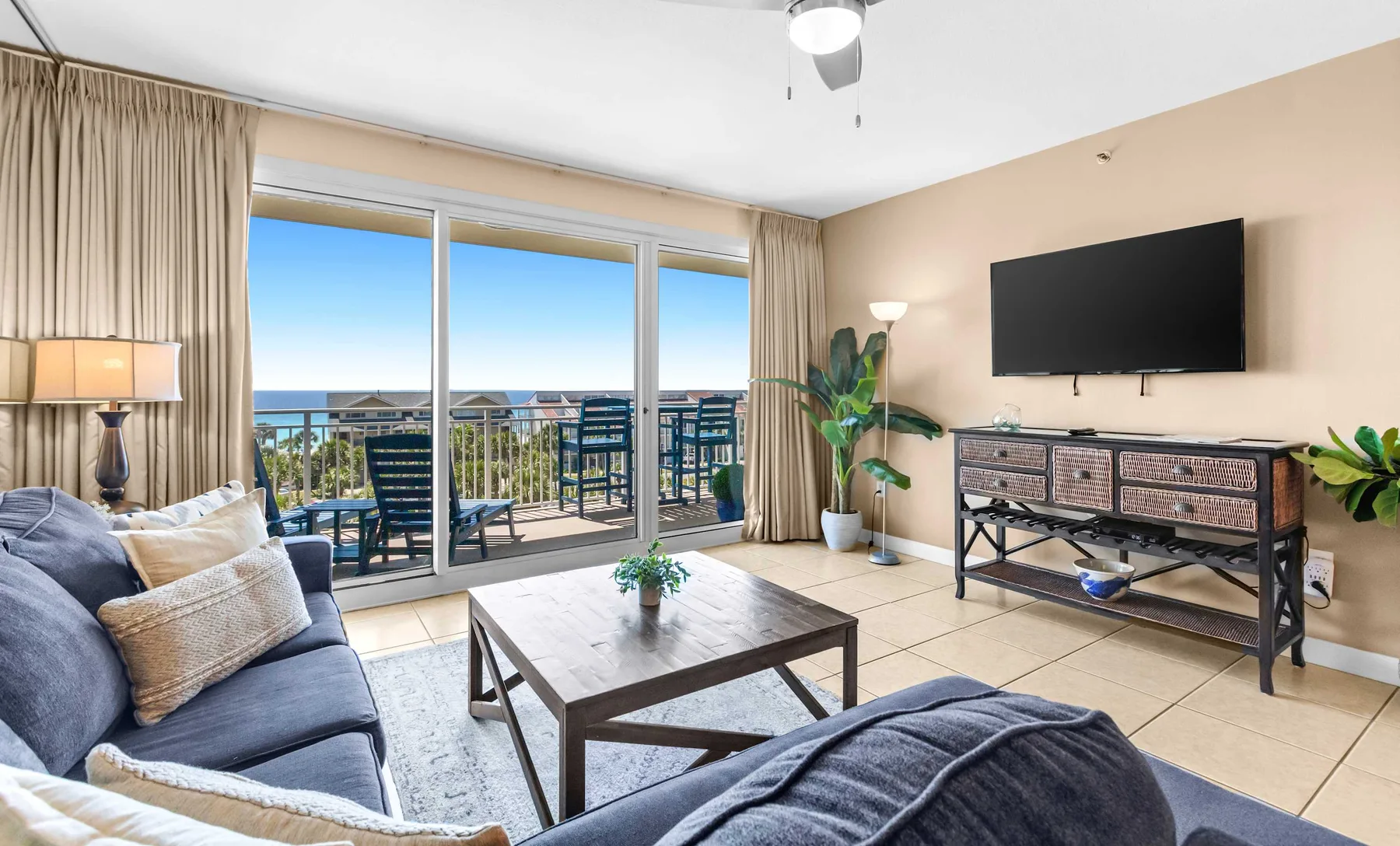 A living room with seating, a coffee table, and glass doors opening onto a balcony.