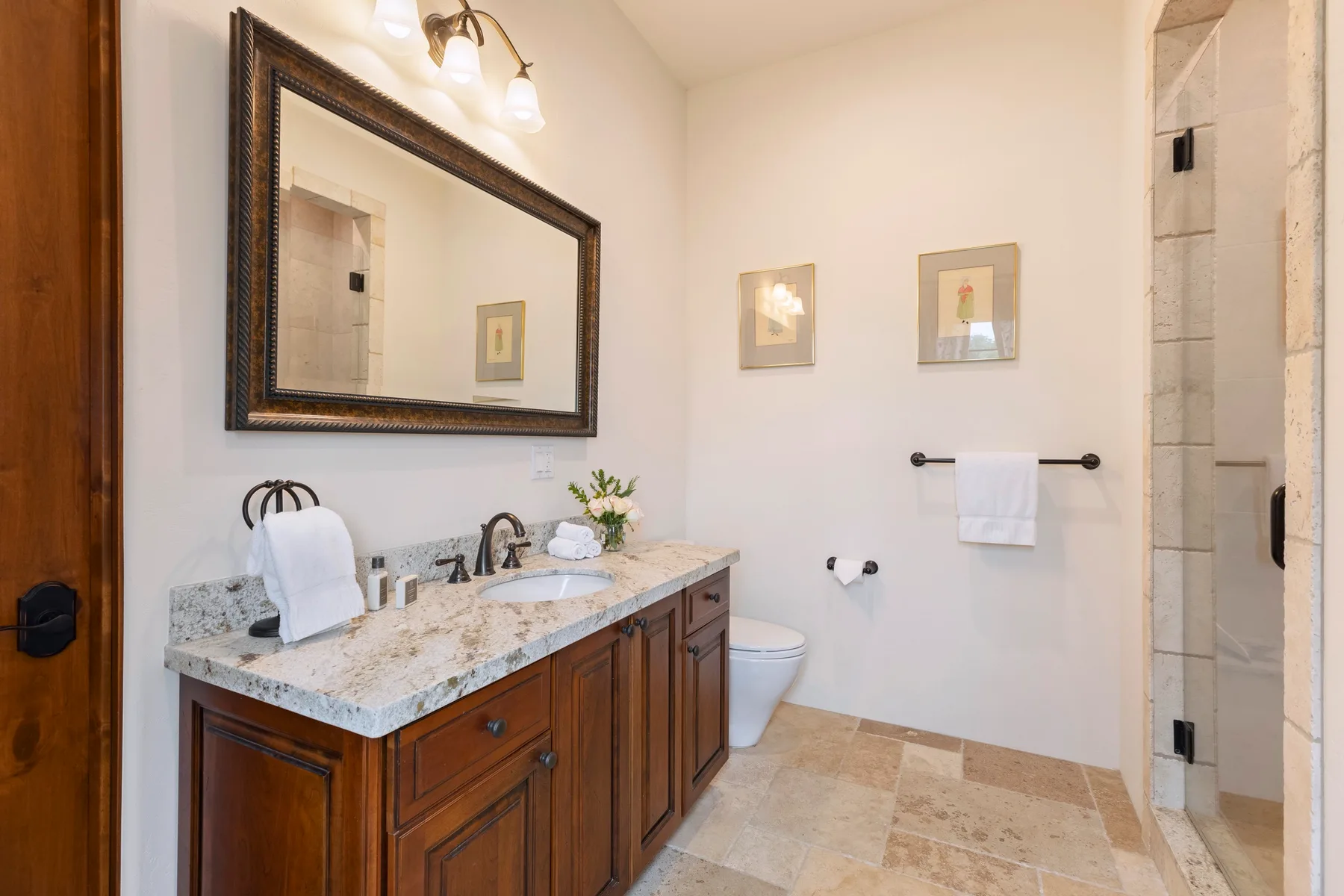 Un baño con mueble de madera, espejo grande y ducha con azulejos.