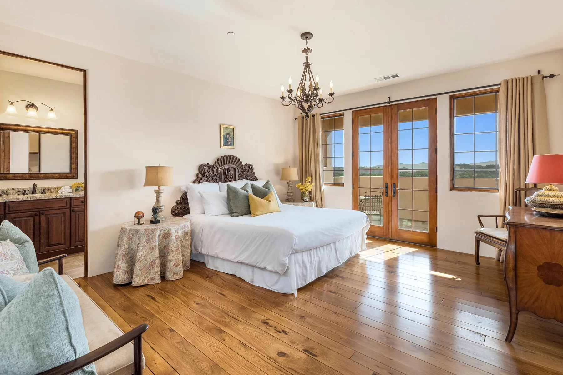 Un dormitorio con una cama grande, asientos y puertas de vidrio con vistas luminosas.