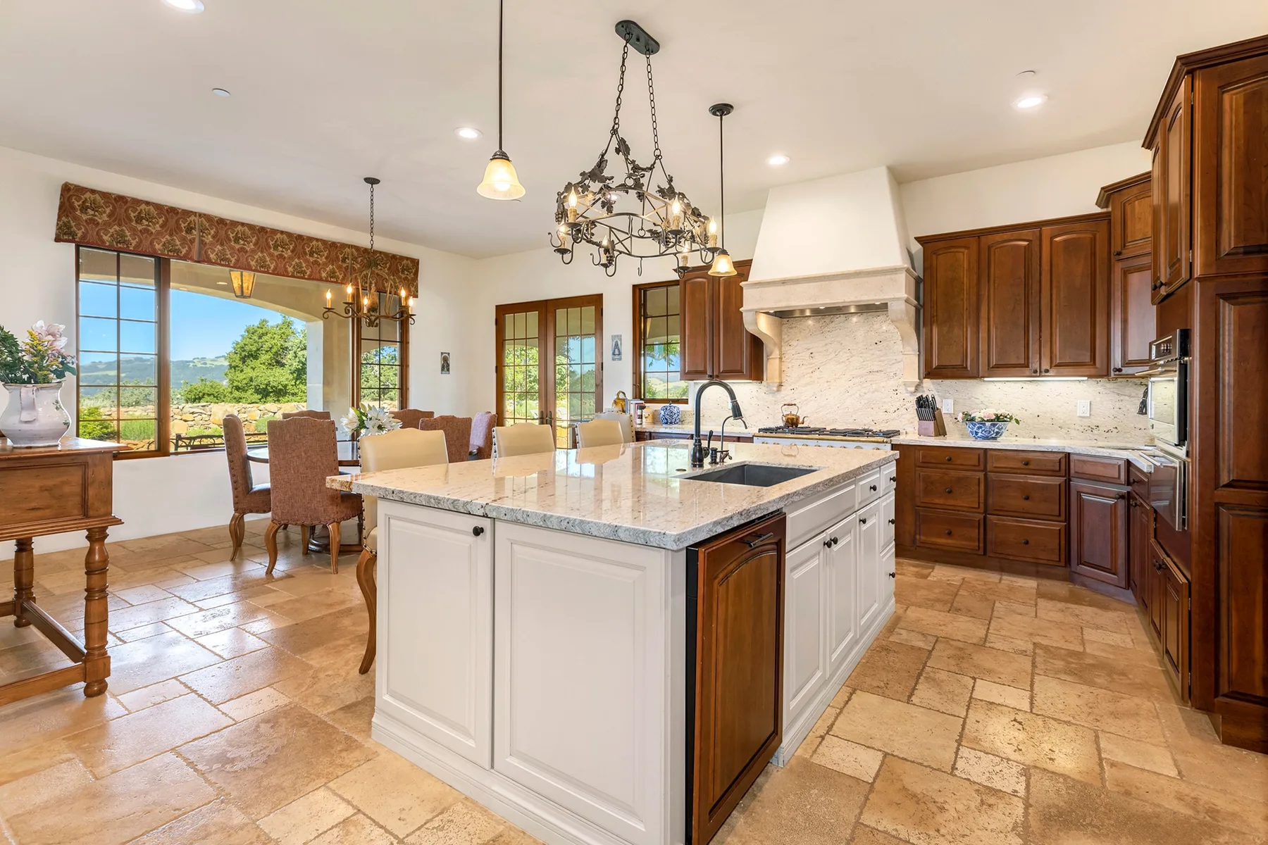 Una cocina amplia con una isla central y un comedor junto a grandes ventanas.