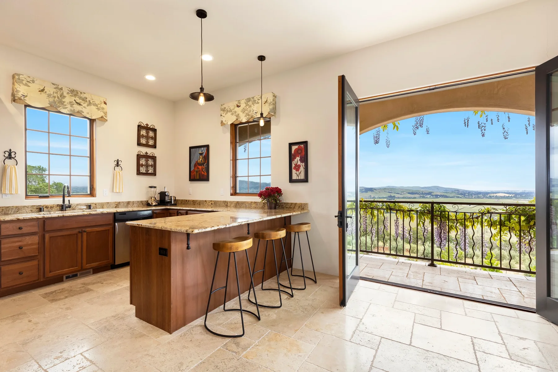 Una cocina luminosa da a un balcón, con una isla central y asientos.