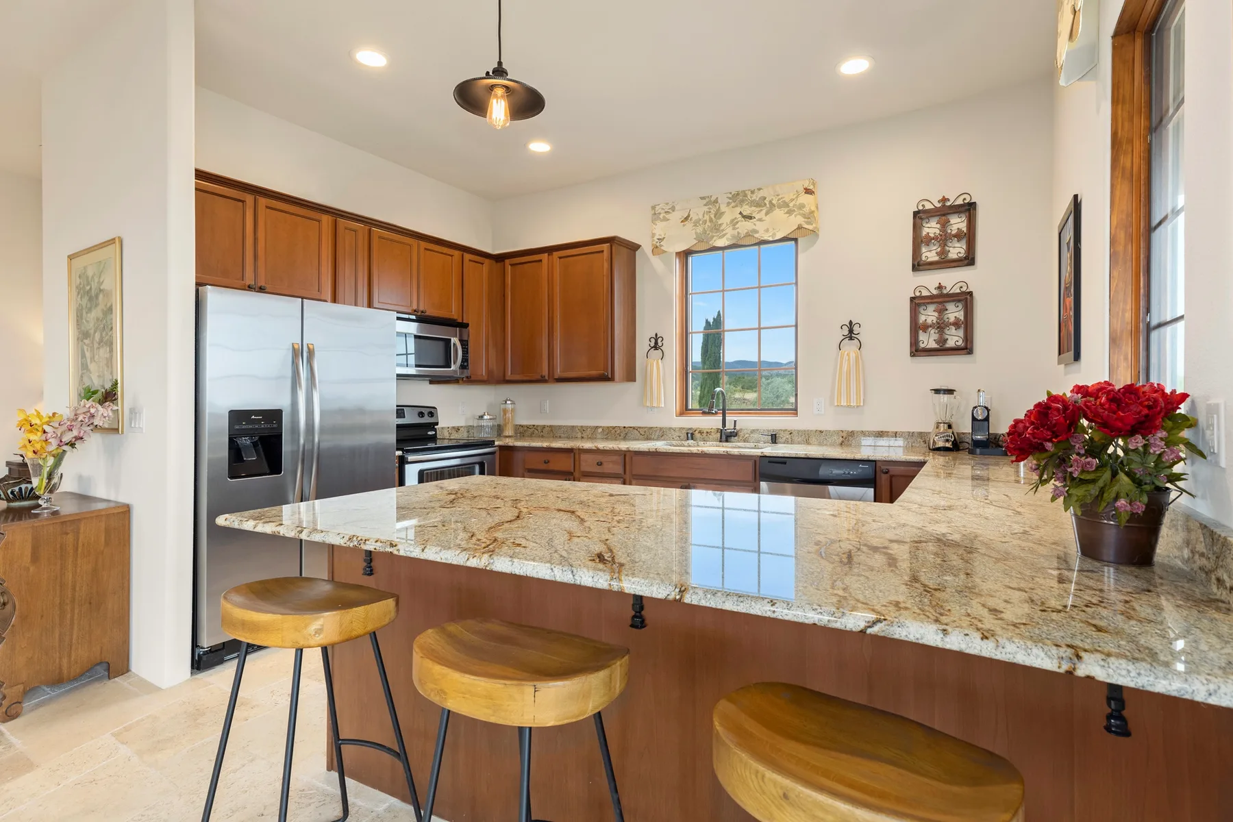 Una cocina luminosa con gabinetes de madera, electrodomésticos de acero inoxidable y una gran isla de piedra.
