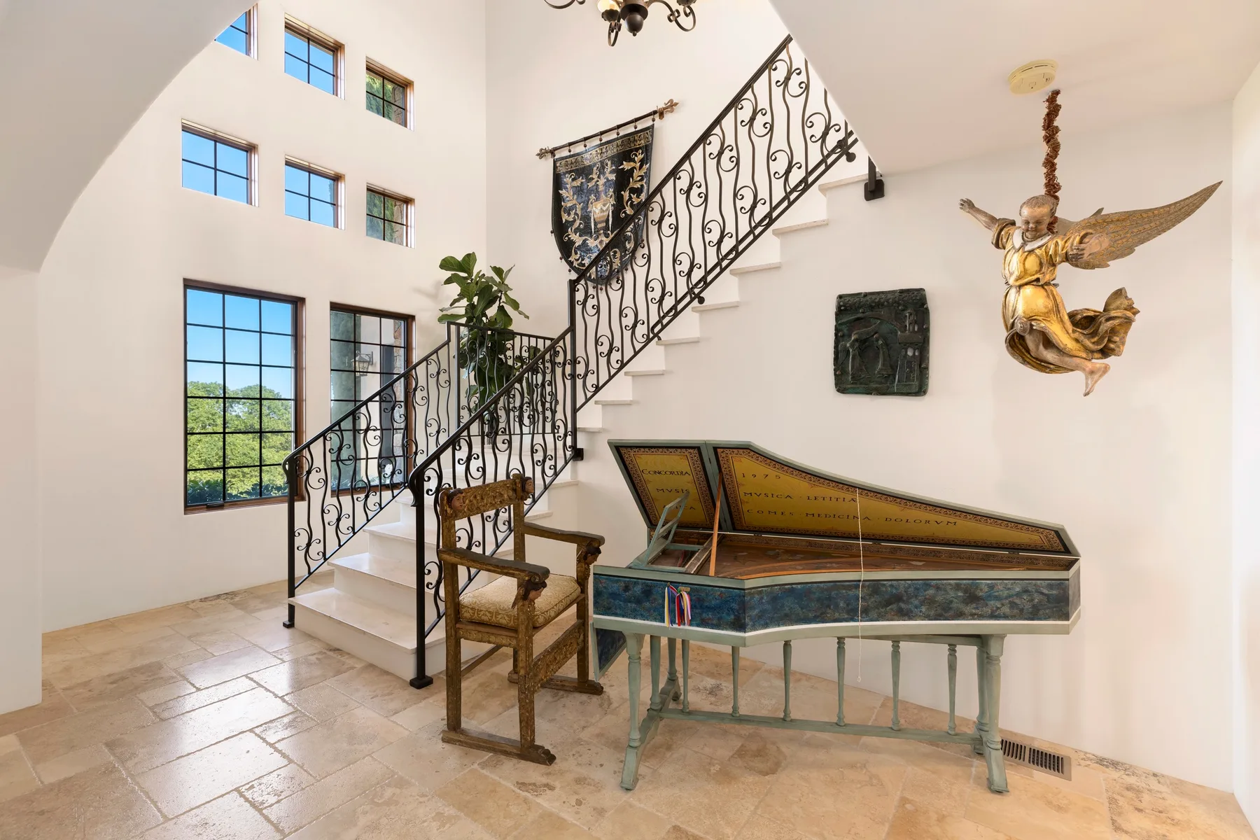 Un interior luminoso con una escalera, ventanas altas y un instrumento de cuerda.
