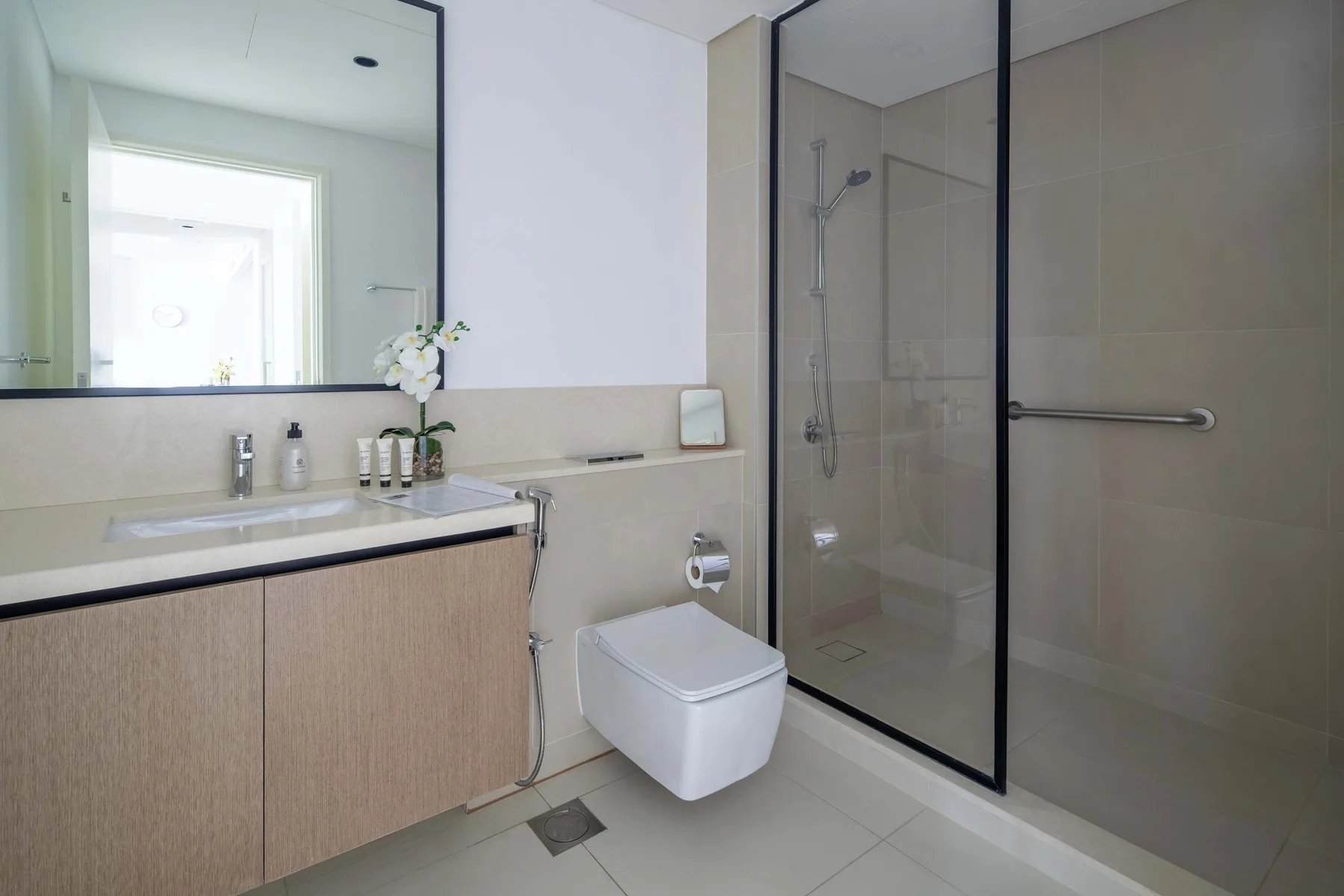 Un baño moderno con lavabo, inodoro y ducha de cristal.