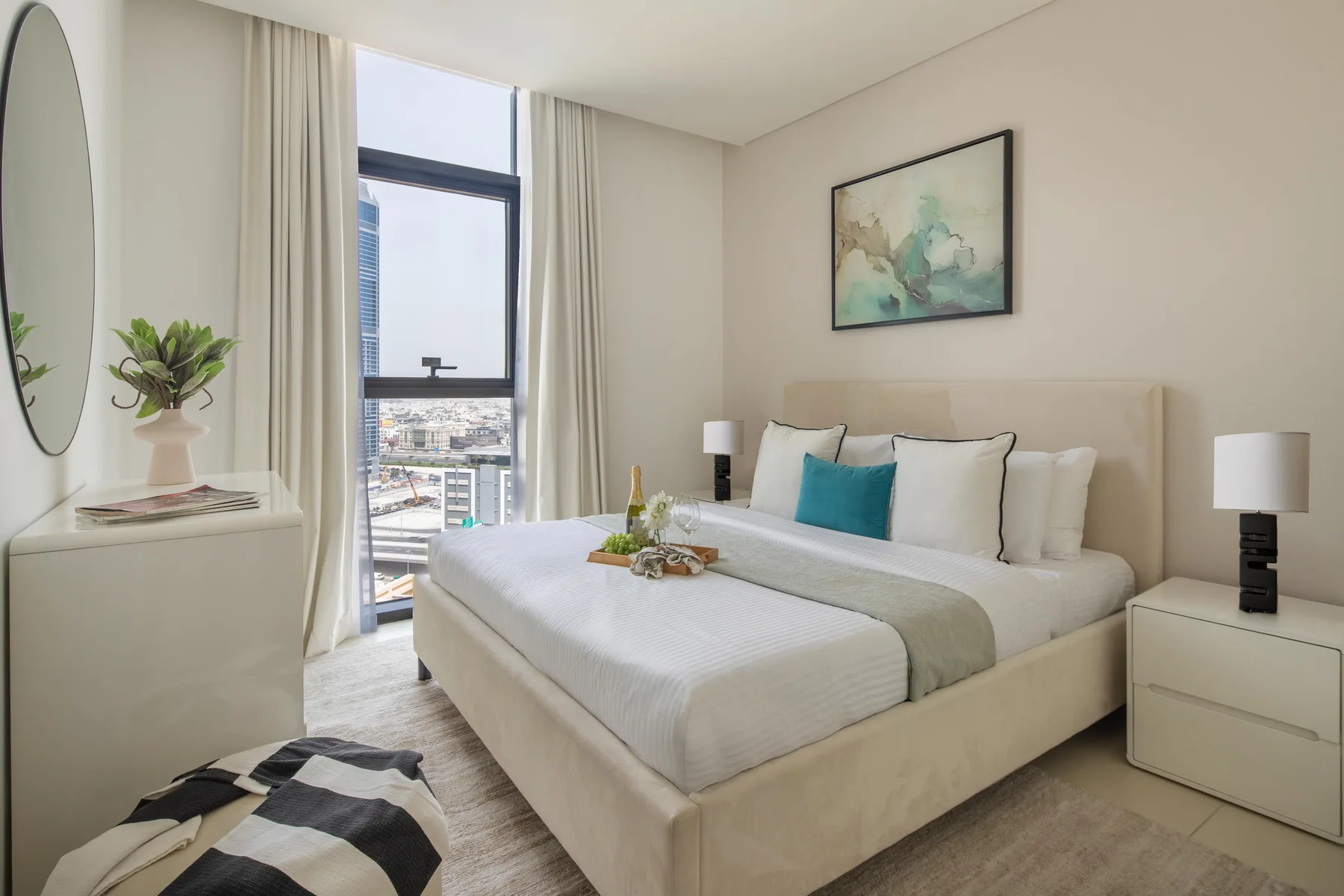 Un dormitorio luminoso con una cama tendida junto a una ventana grande.