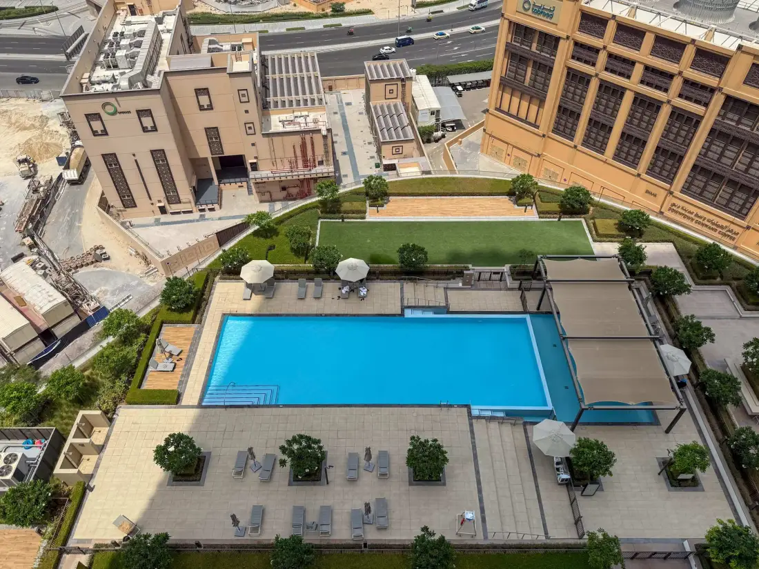 Una piscina al aire libre está junto a una terraza pavimentada con asientos.