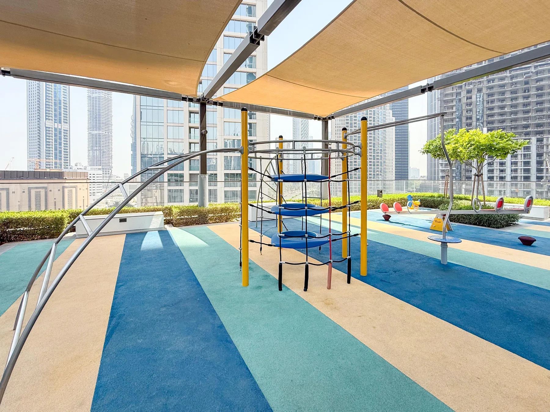 Un parque infantil al aire libre con juegos para trepar y suelo acolchado.