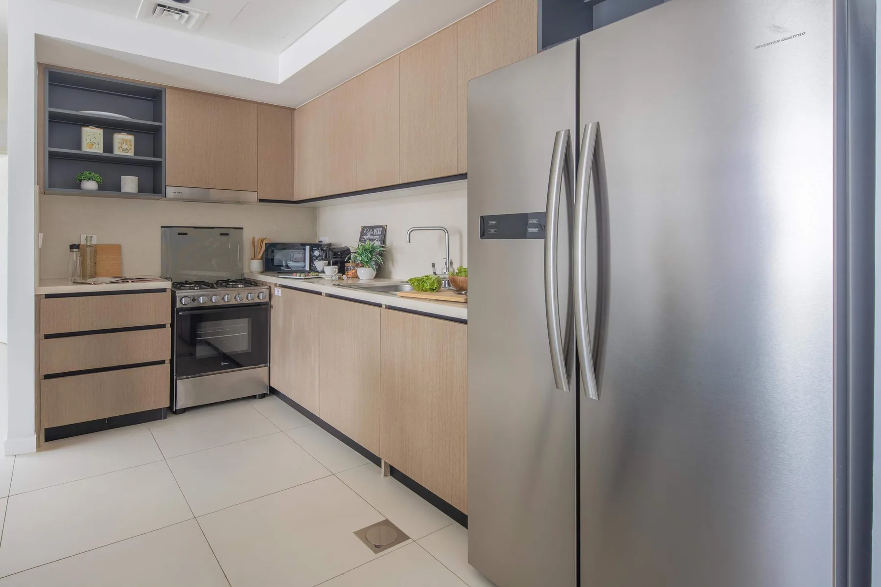 Una cocina moderna con gabinetes de madera clara, una estufa y un refrigerador de acero inoxidable.