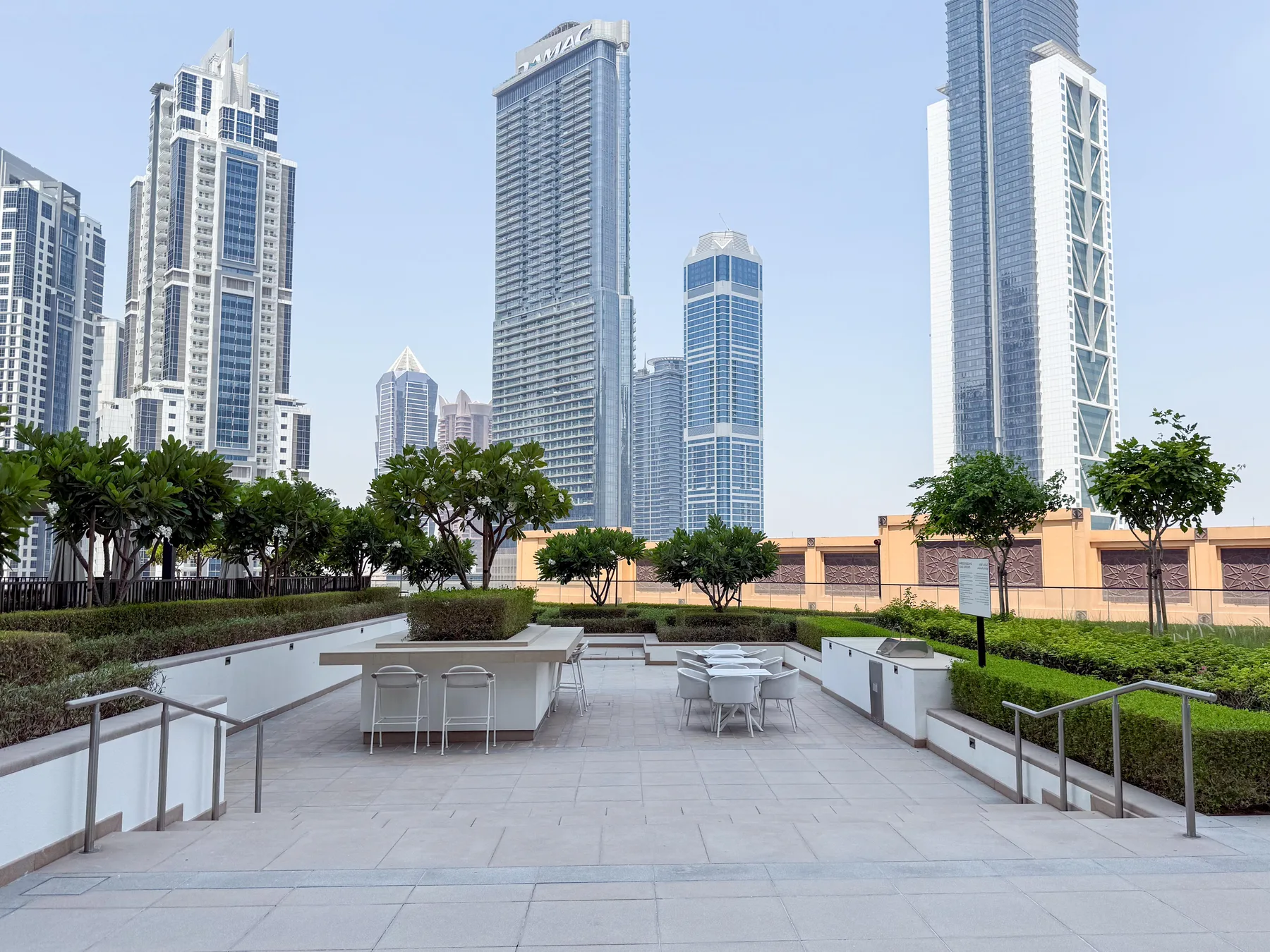 Una terraza pavimentada con asientos da a una zona ajardinada y al horizonte urbano.